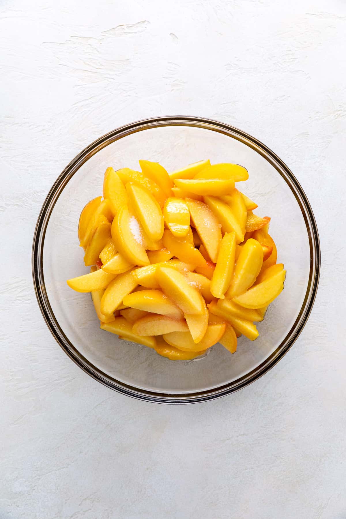 Peach slices with sugar in a bowl.