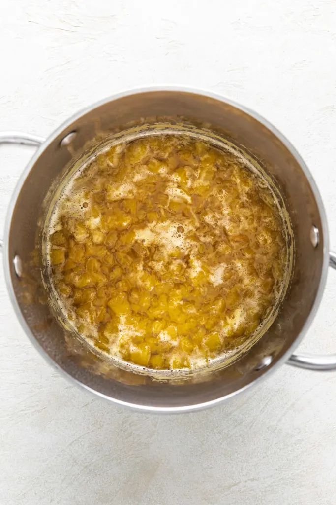 Peach simple syrup cooking in a pan.