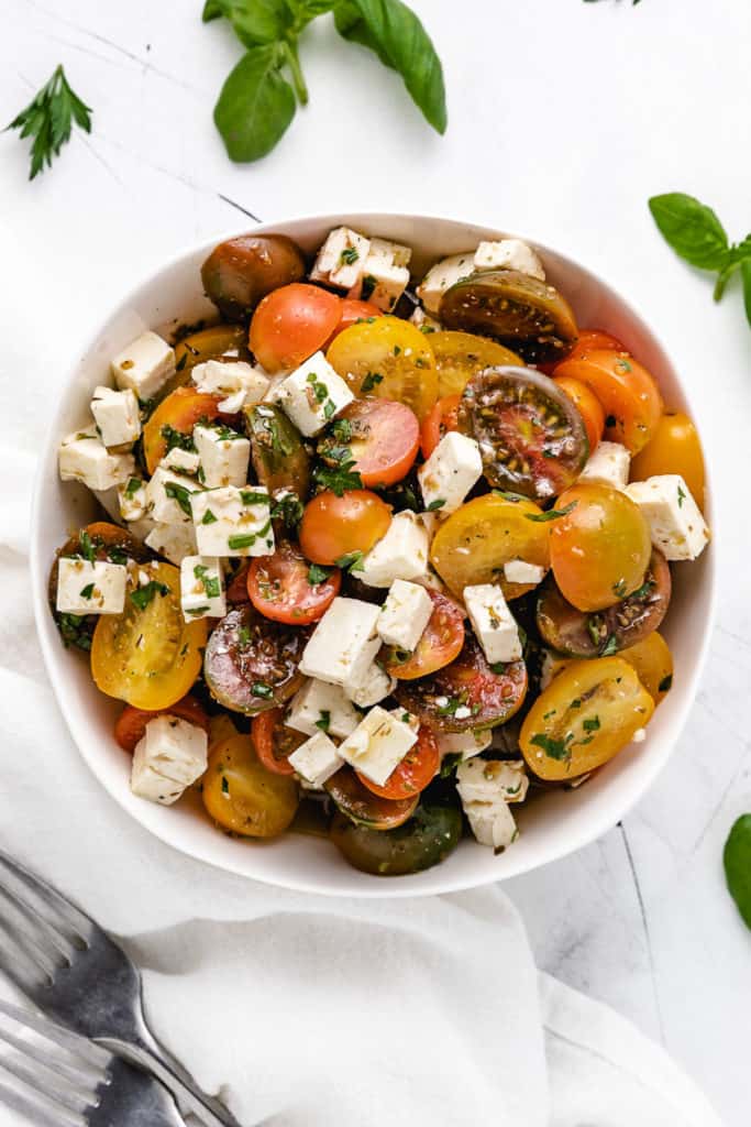 Top down view of a bowl of tomato salad tossed with feta cheese.