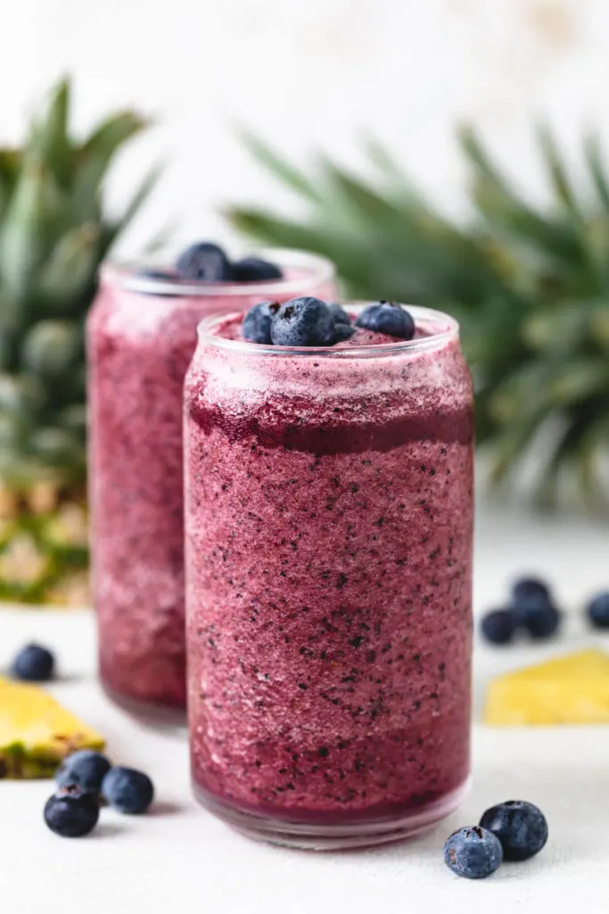 Blueberries and pineapple next to smoothies.