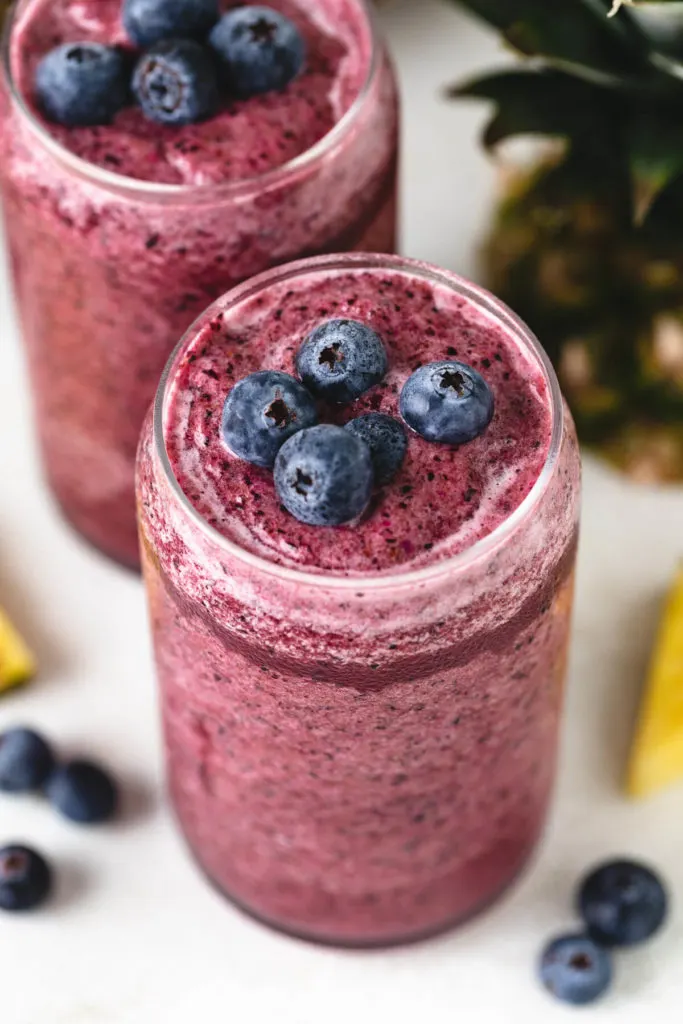 Angled view of two smoothies with fruit.