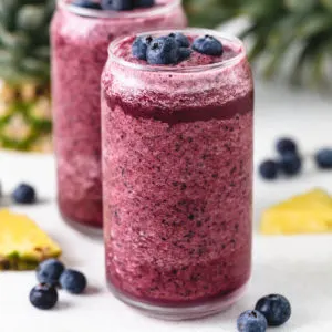 Side view of two glasses of blueberry pineapple smoothies.