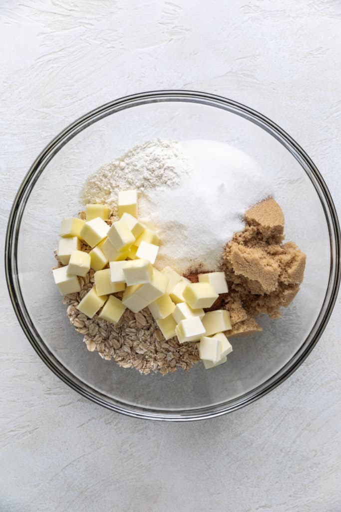 Oats, brown sugar, granulated sugar, butter, and flour in a glass bowl.