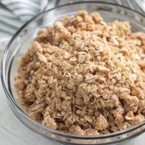 Close up view of crumble topping with oats in large glass bowl.