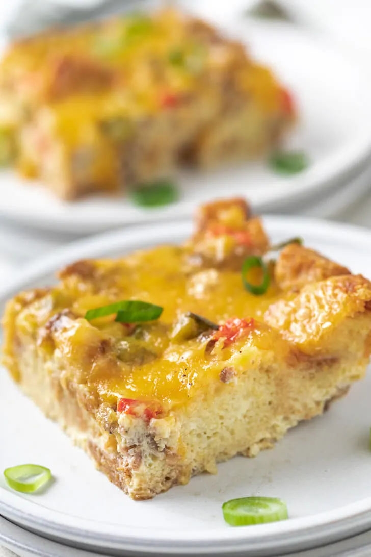 Casserole topped with green onions on a stack of plates.