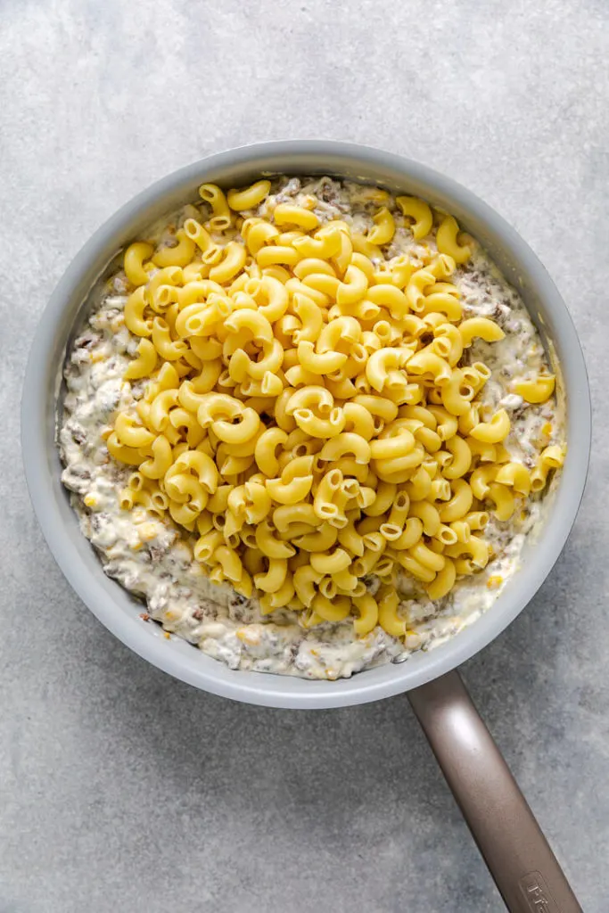 Elbow noodles poured over a pan of sauce, corn, and hamburger.