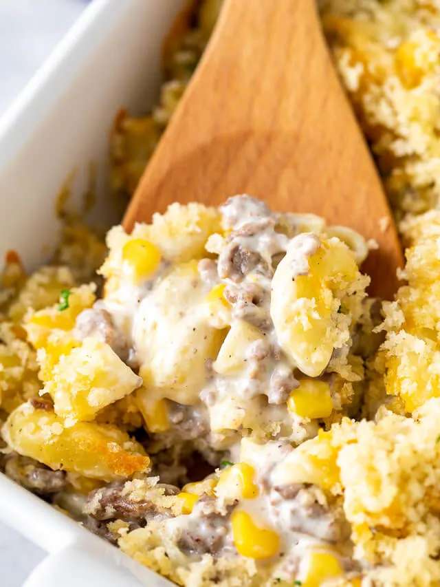 Wooden spoon scooping casserole out of a pan.