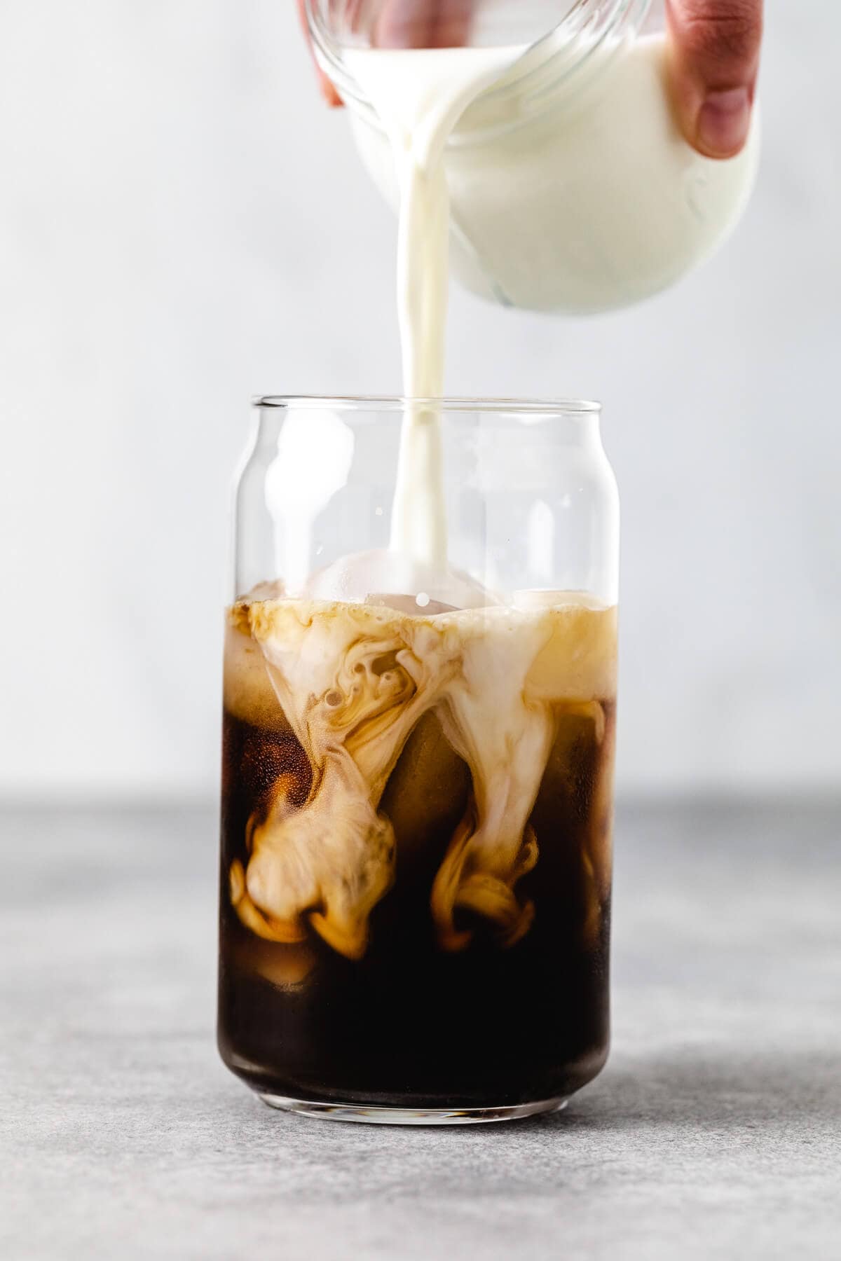 Milk being poured into an iced latte.