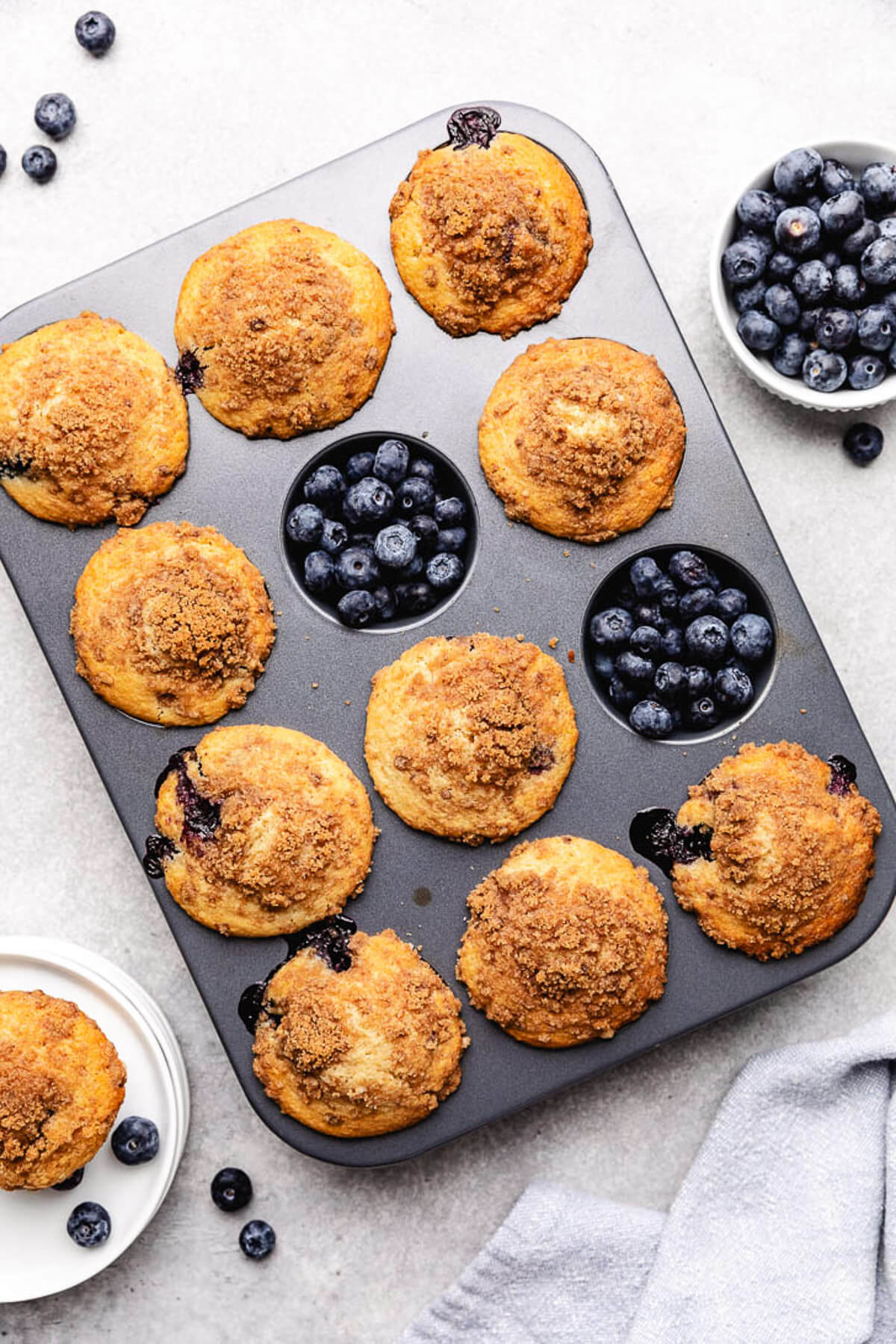 Close up view of muffins and blueberries in a muffin pan.