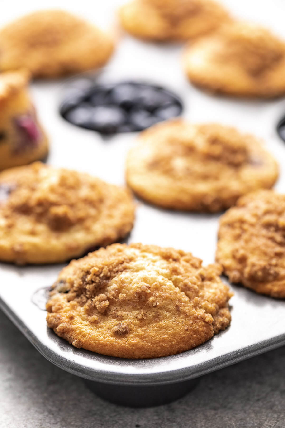 Side view of baked muffin with crumb topping in a pan.