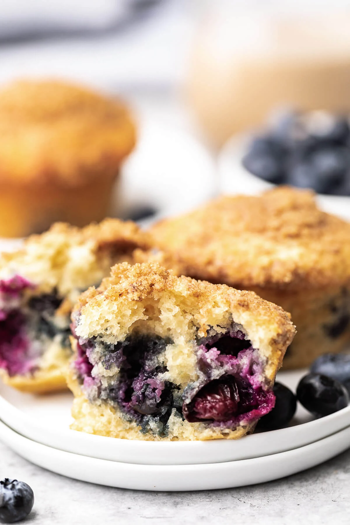 Blueberry Muffins Fresh blueberries next to muffins on white dishes.