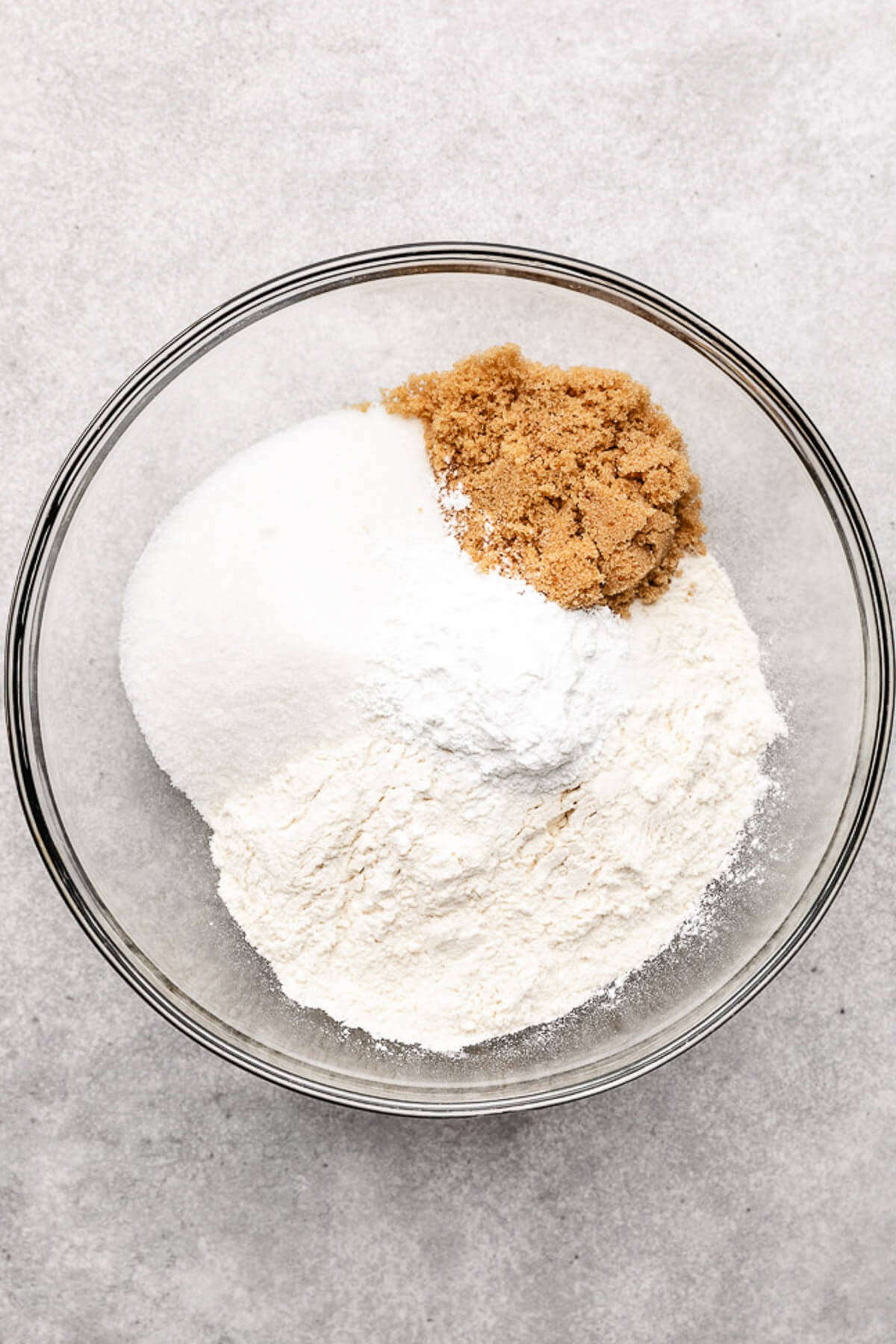Sugar, baking powder, and flour in a glass bowl.