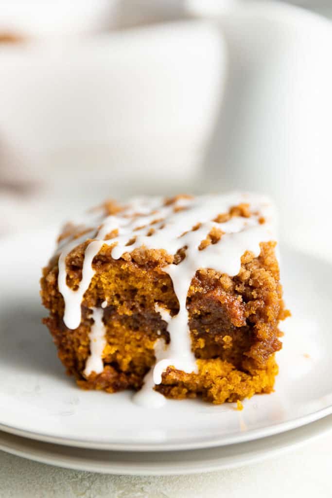 Pumpkin coffee cake with streusel and glaze on a stack of plates.