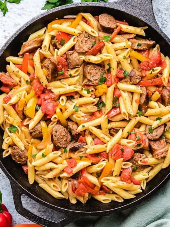Top down view of peppers and sausage pasta in cast iron.