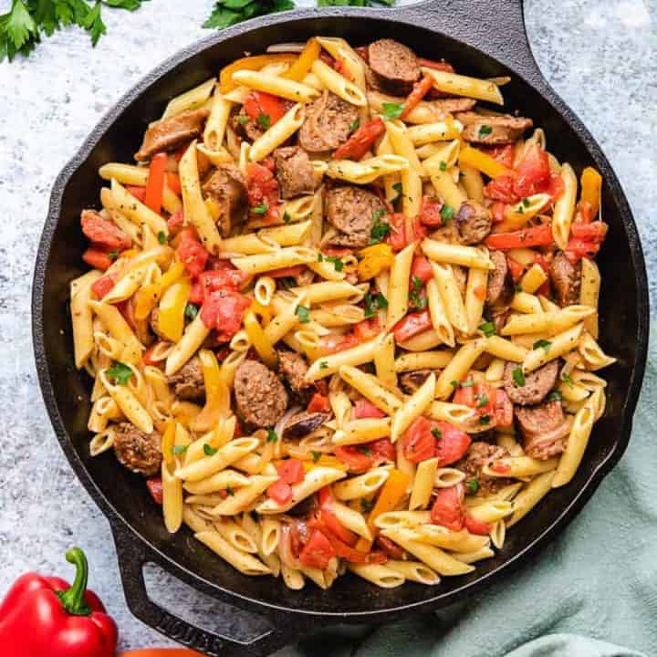 Top down view of peppers and sausage pasta in cast iron.