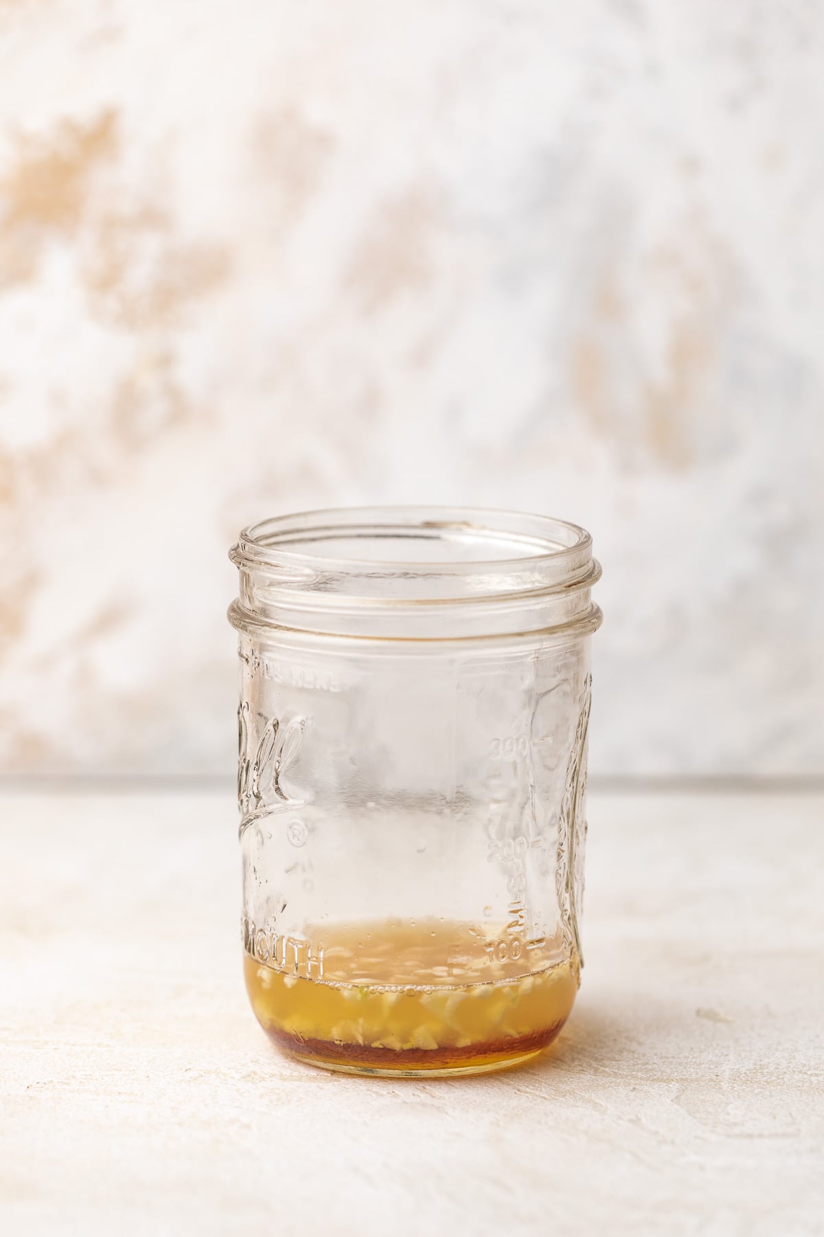 Apple cider vinegar, honey, lemon juice, garlic, and seasonings in a jar.