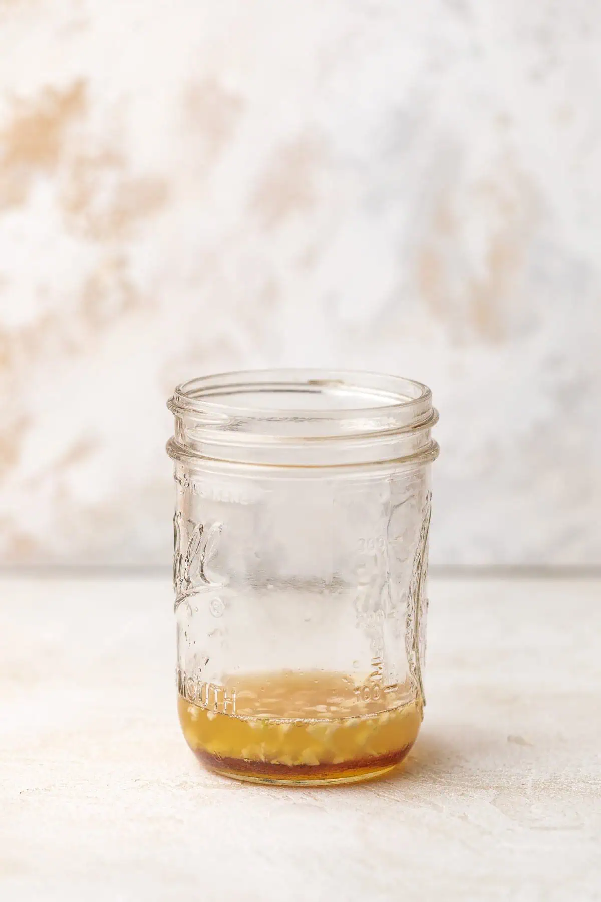 Apple cider vinegar, honey, lemon juice, garlic, and seasonings in a jar.