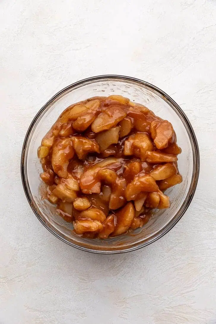 Apple pie filling stirred with apple pie spice in a bowl.