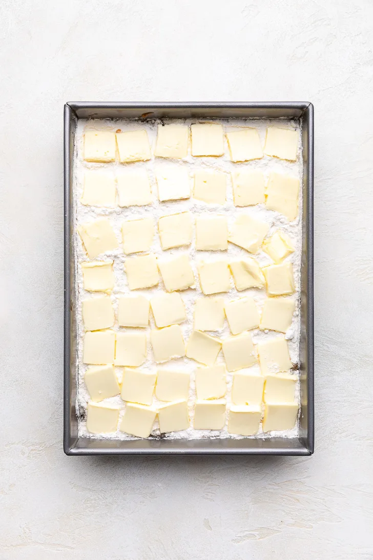 Sliced butter on top of cake mix in a pan.