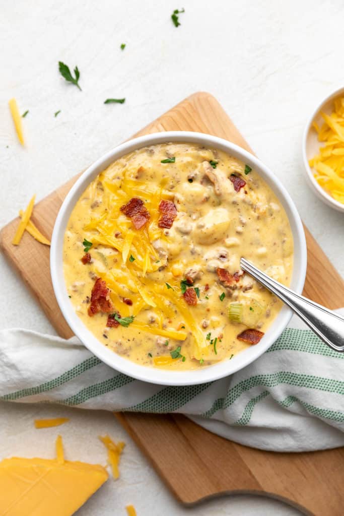 Top down view of a bowl of cheesy bacon cheeseburger soup with a spoon.