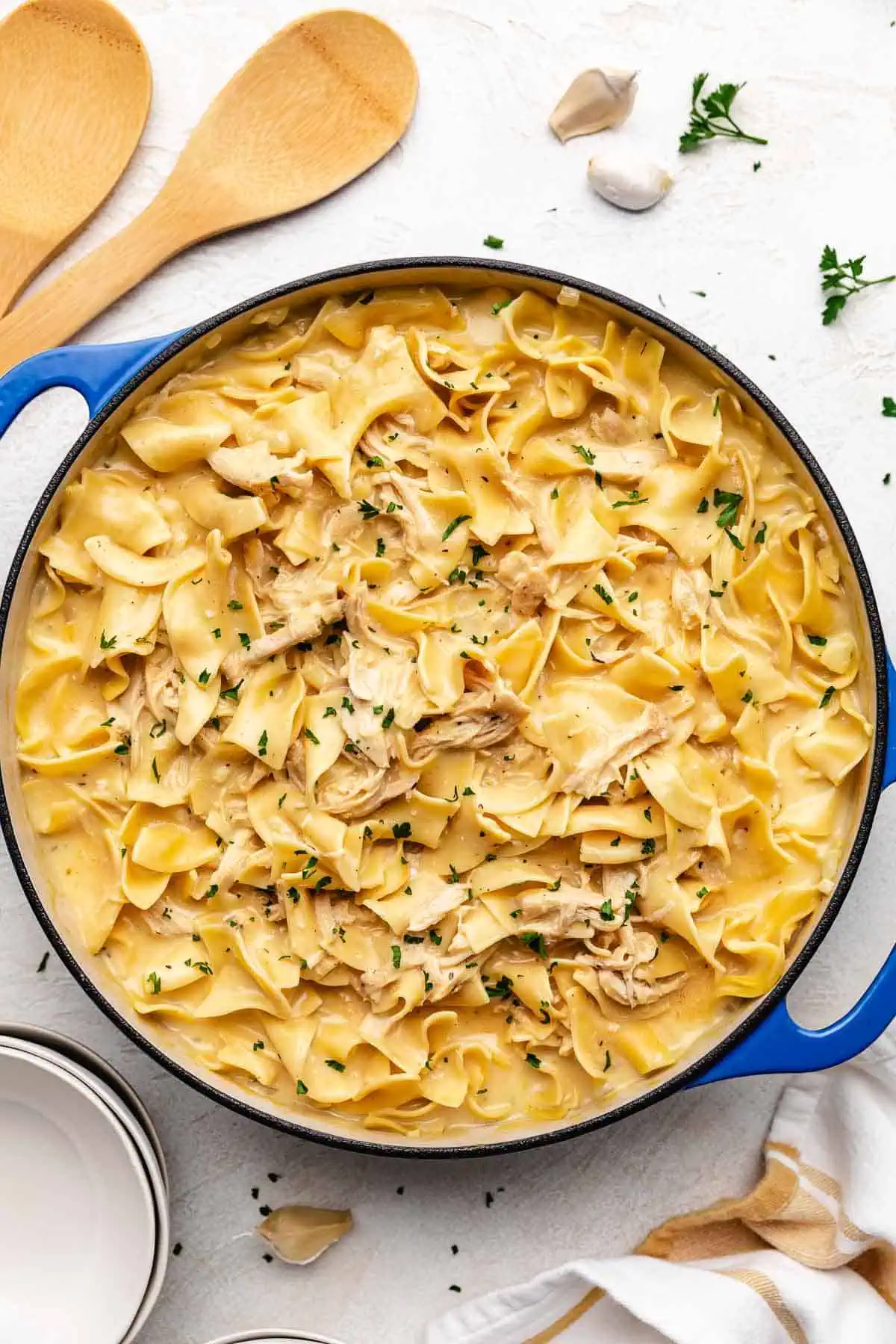 Top down view of chicken and noodles in a blue pan.