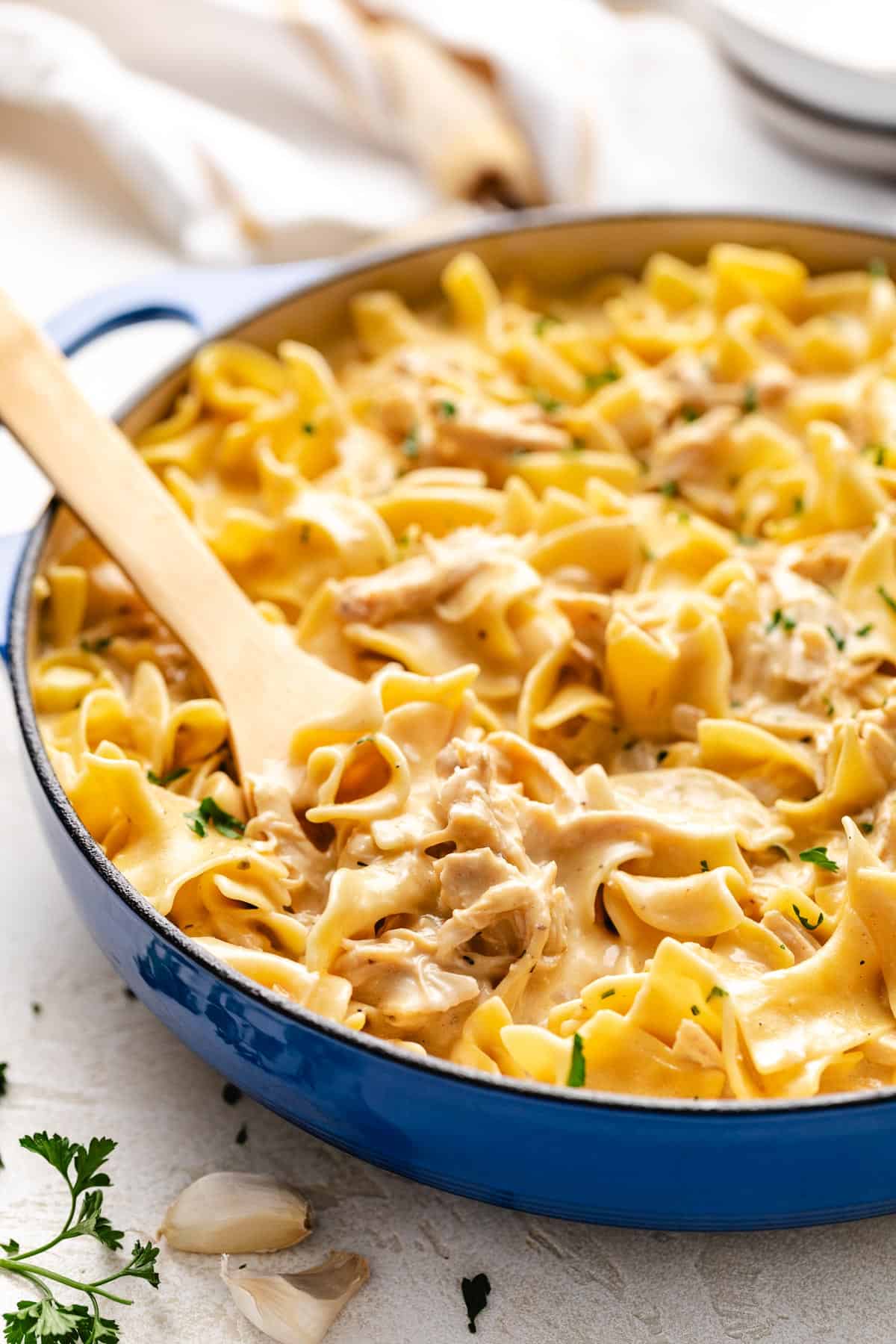 Blue pan holding egg noodles and shredded chicken.