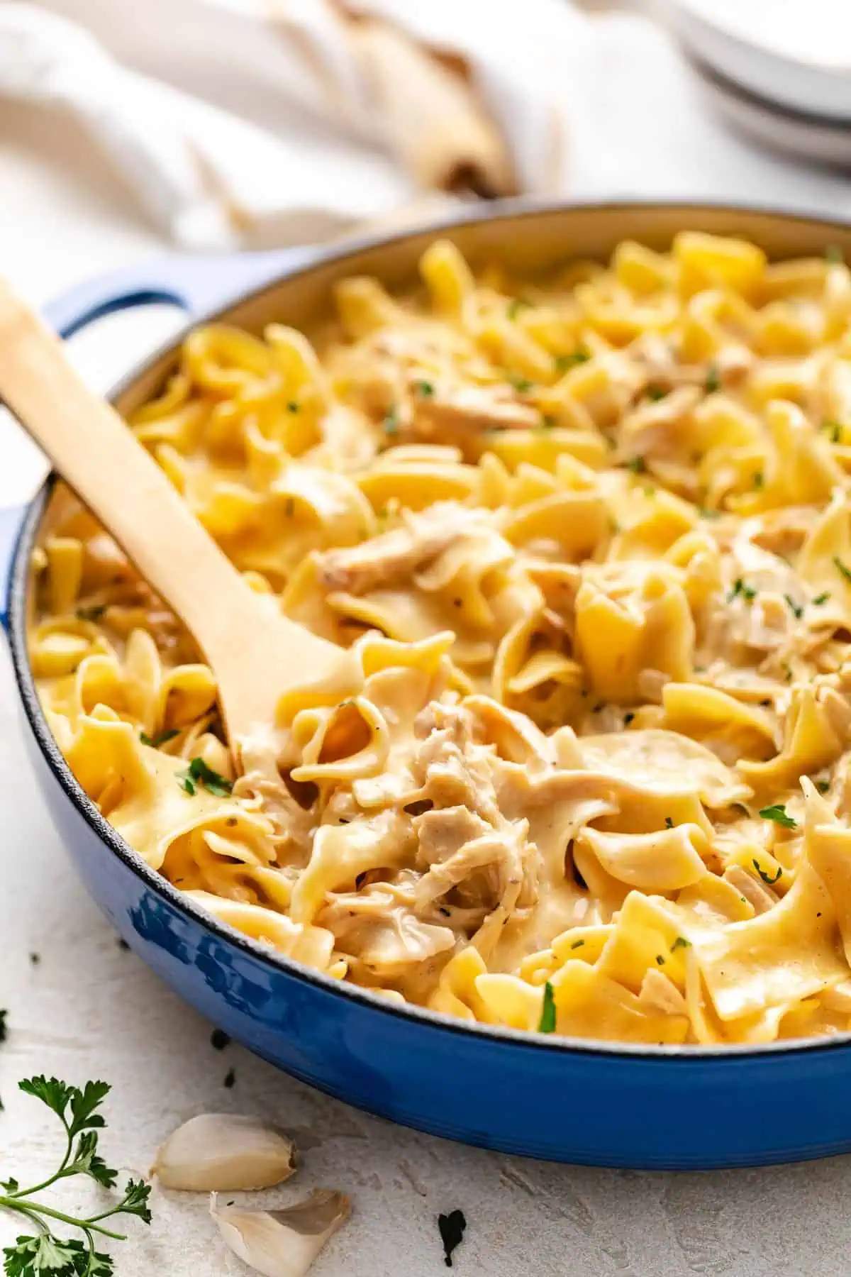 Blue pan holding egg noodles and shredded chicken.