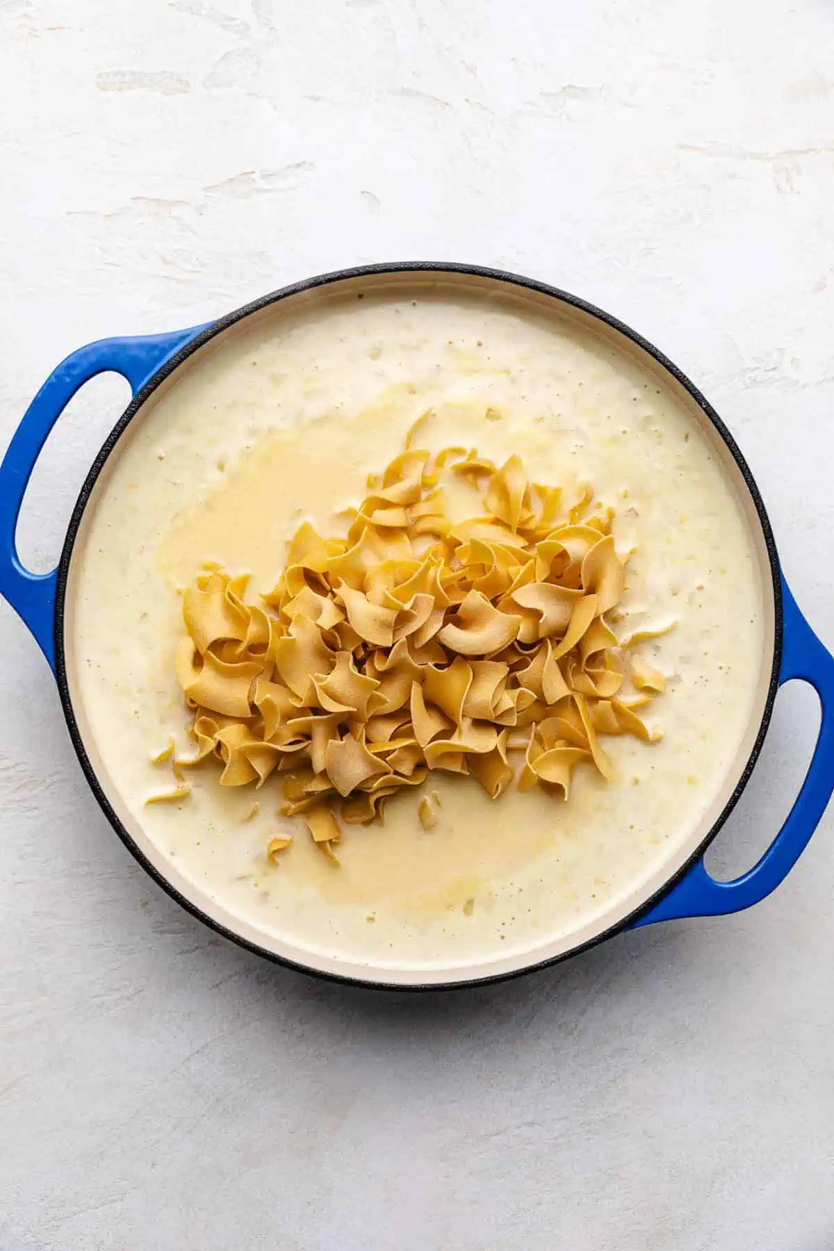 Uncooked noodles added to broth, cream of chicken soup, water, and heavy cream.