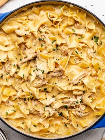 Close up view of a pan of egg noodles tossed with sauce and chicken.