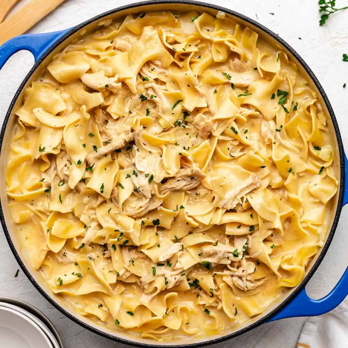 Close up view of a pan of egg noodles tossed with sauce and chicken.