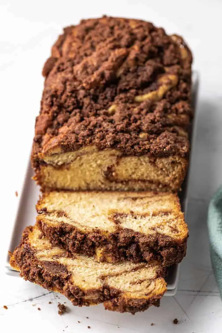 Sliced loaf of bread topped with crunchy cinnamon on white plates.