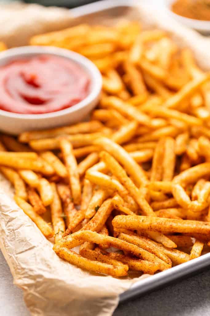 Side view of seasoned french fries on parchment paper.