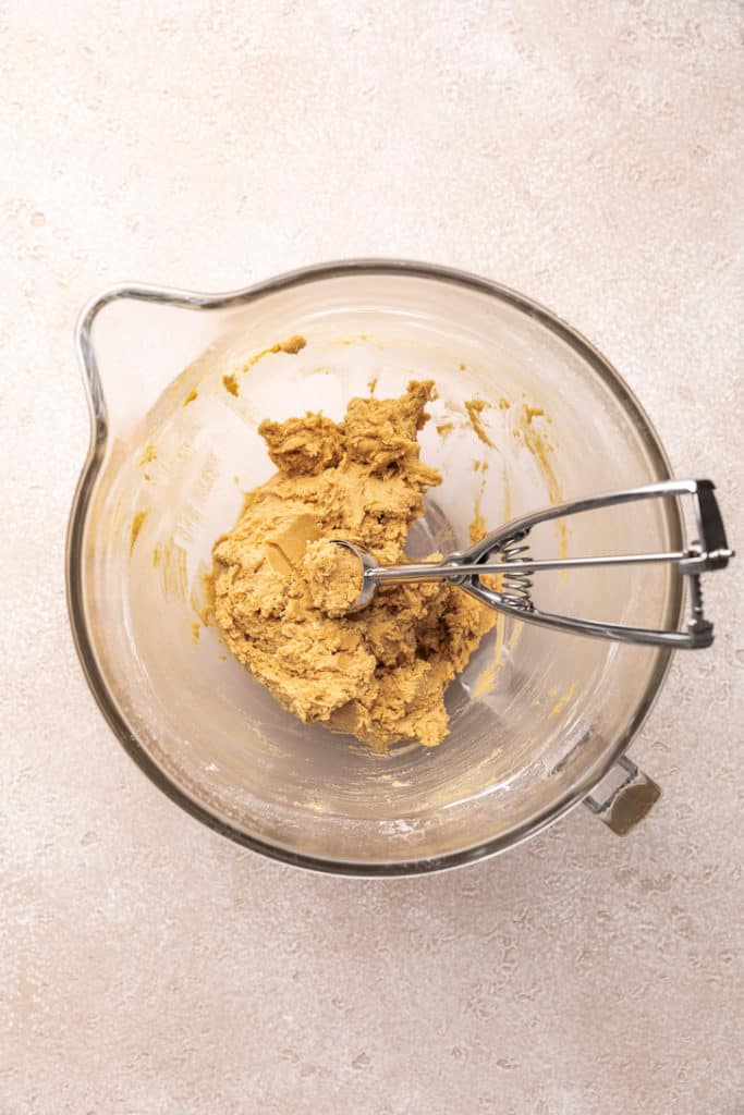 Cookie scoop in a bowl of cookie dough.