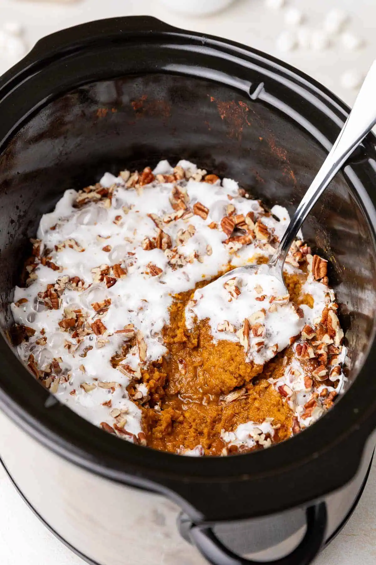 Close up view of a metal spoon in a crock pot of casserole.