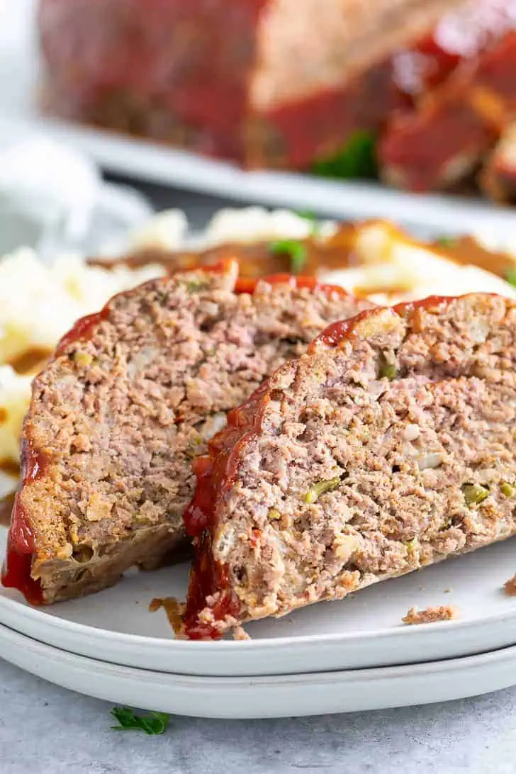 Pieces of homemade meatloaf on two plates.