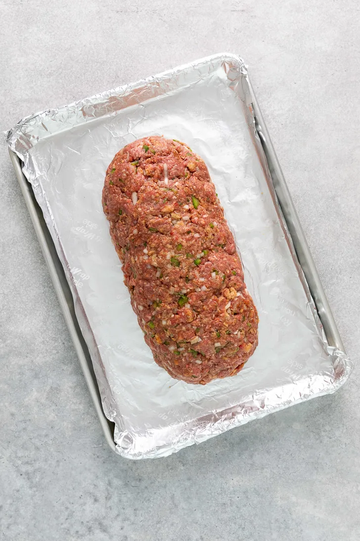 Meatloaf in a log shape on a sheet pan.