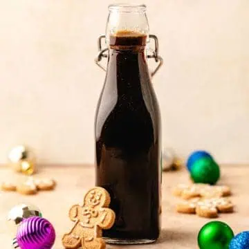 Close up view of gingerbread syrup in a jar next to a cookie.