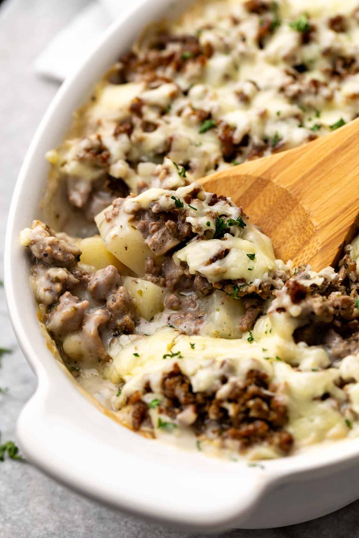 Close up view of a pan of ground beef and potato casserole with a spoon.