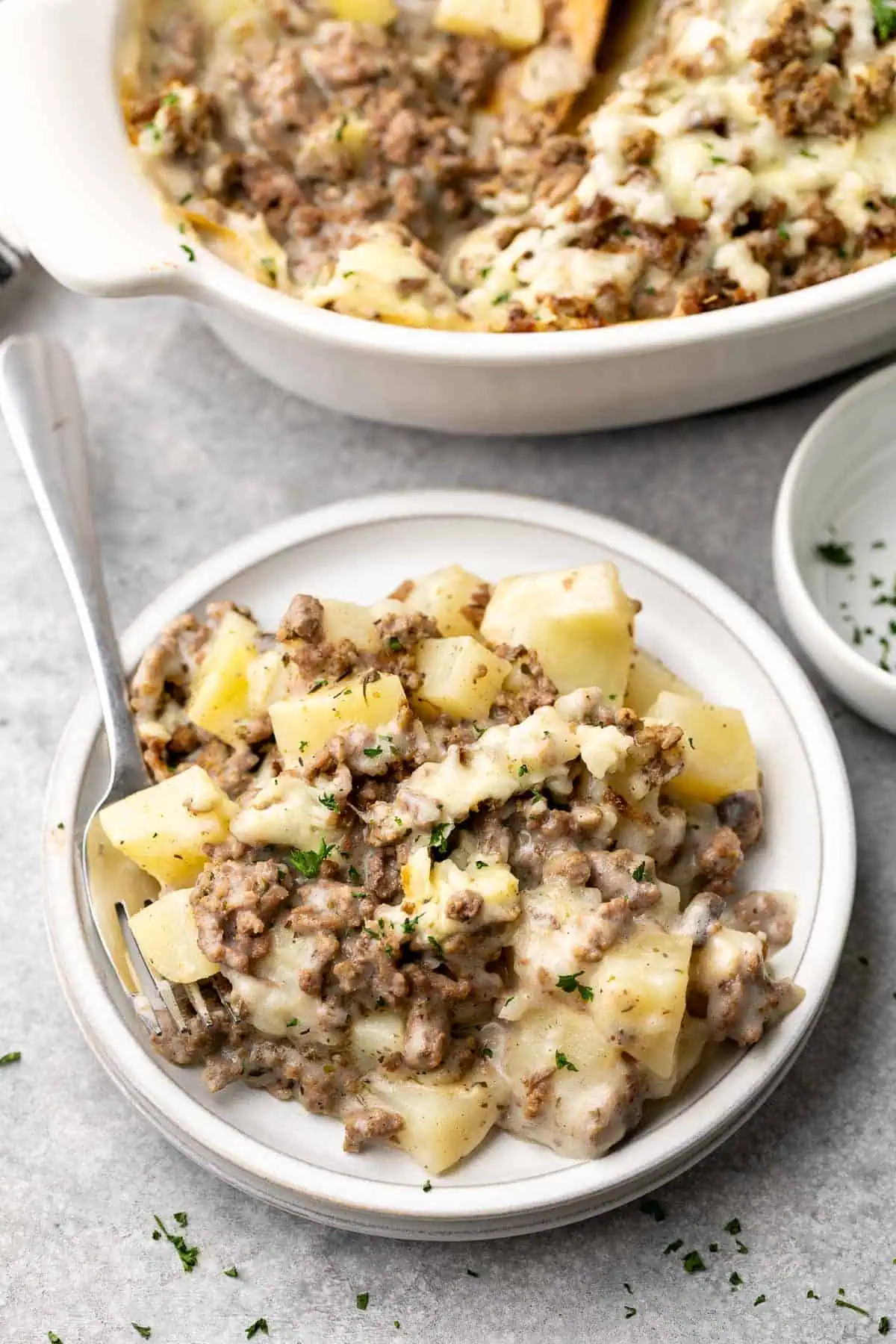 Cheesy potato and beef casserole on a gray plate.