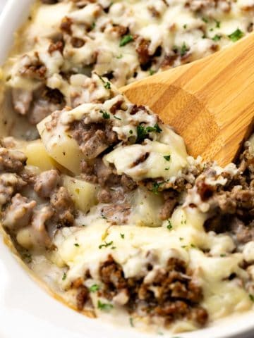 Spoon scooping potatoes and ground beef from a dish.