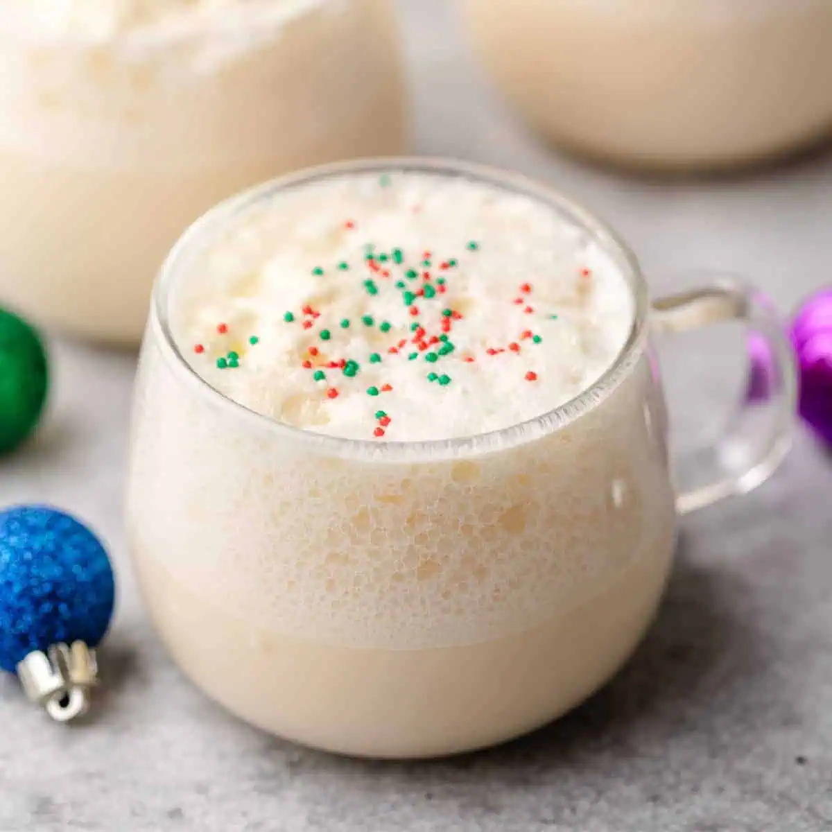 Christmas ornaments next to a glass of punch.