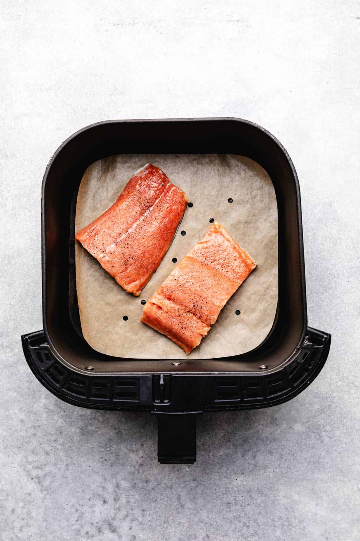Two uncooked salmon filets in a basket.