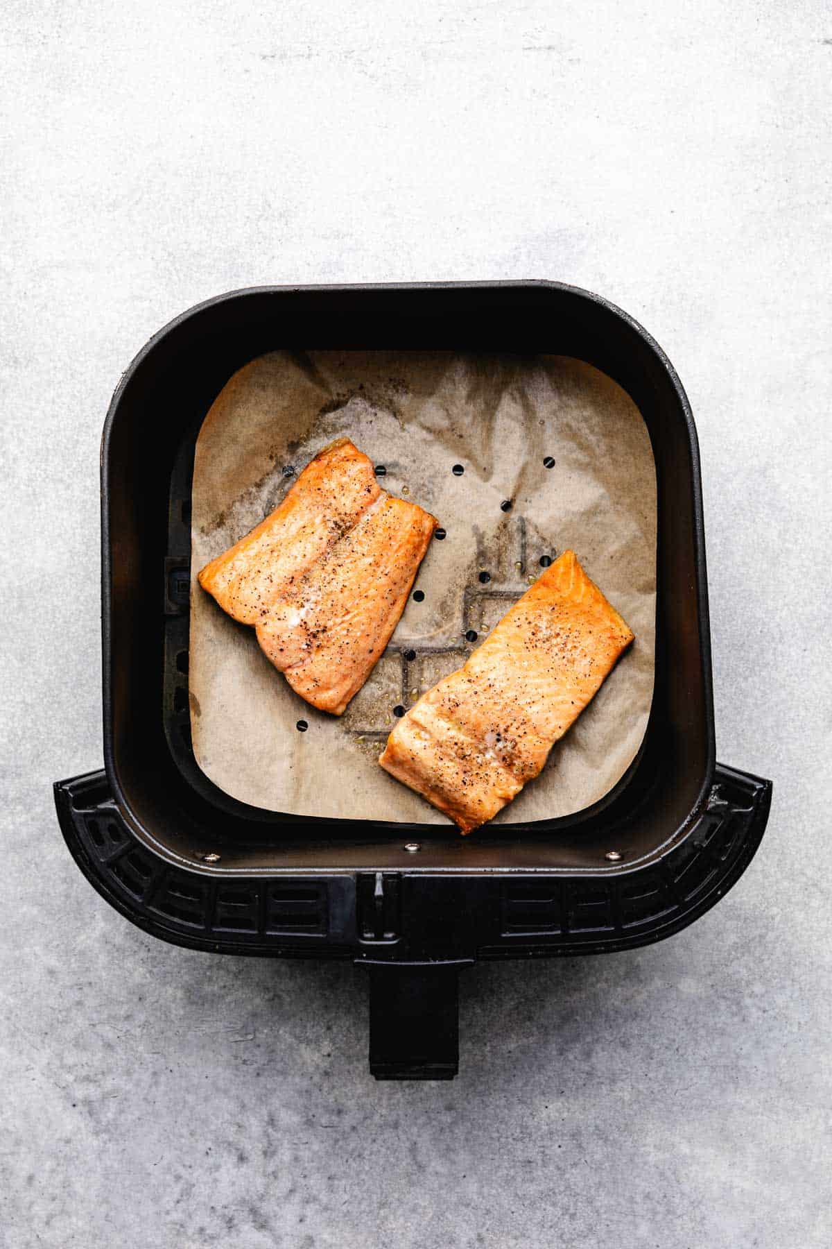 Two pieces of fresh salmon in an air fryer basket.