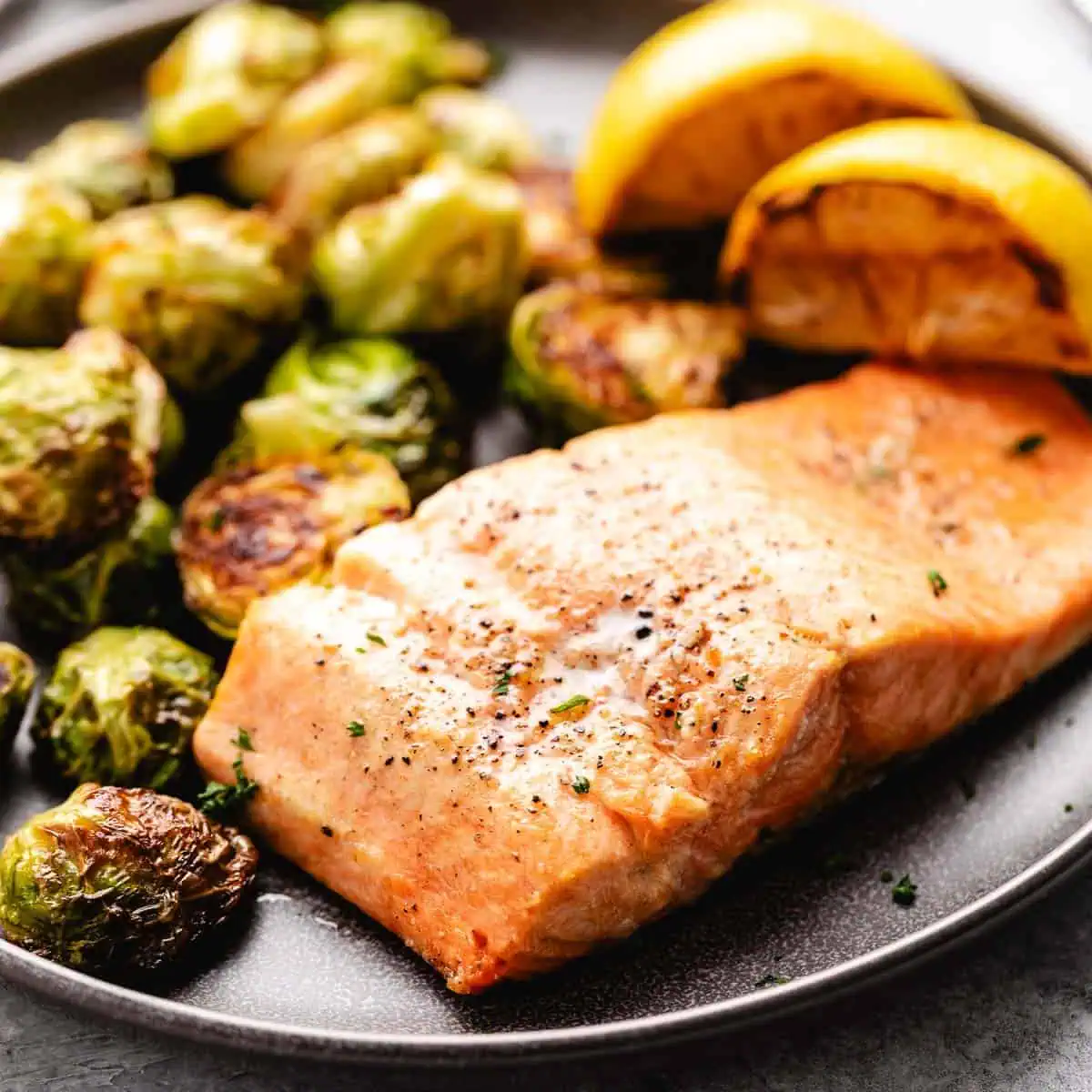 Side view of freshly cooked air fryer salmon next to veggies.