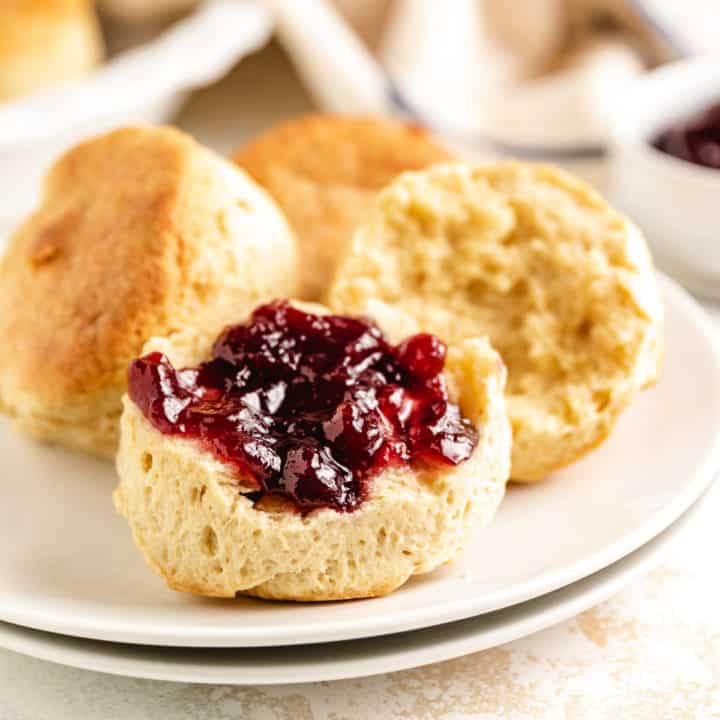 Buttermilk biscuits on a plate with grape jelly.