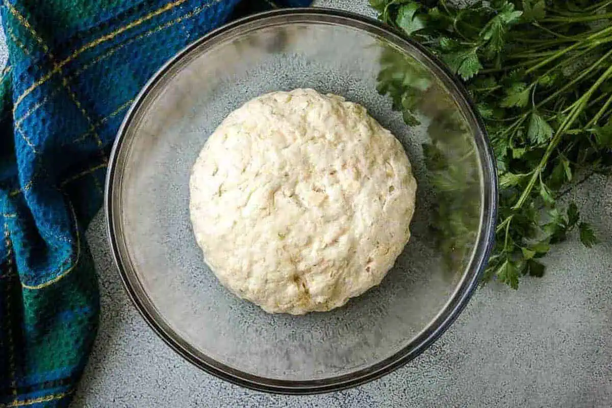 Risen bread dough in a glass bowl.