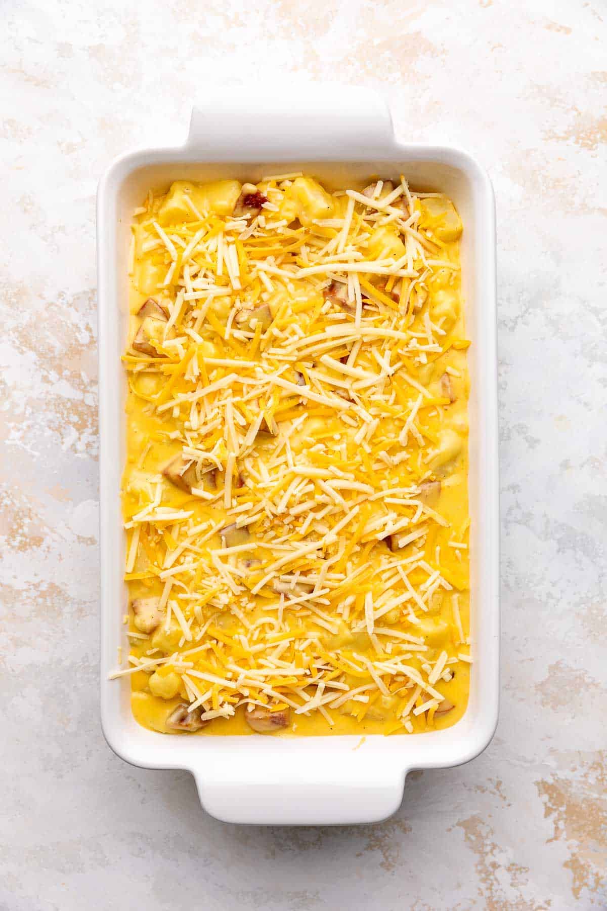 Shredded cheese sprinkled over cheese, sausage and potatoes.