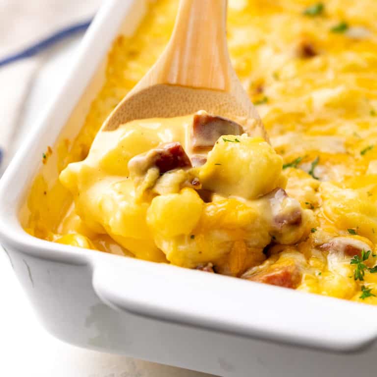 Close up view of cheesy potatoes and sausage in a pan.
