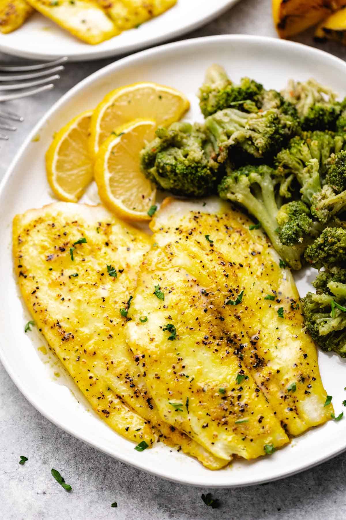 Fillets of flounder on a plate with broccoli.
