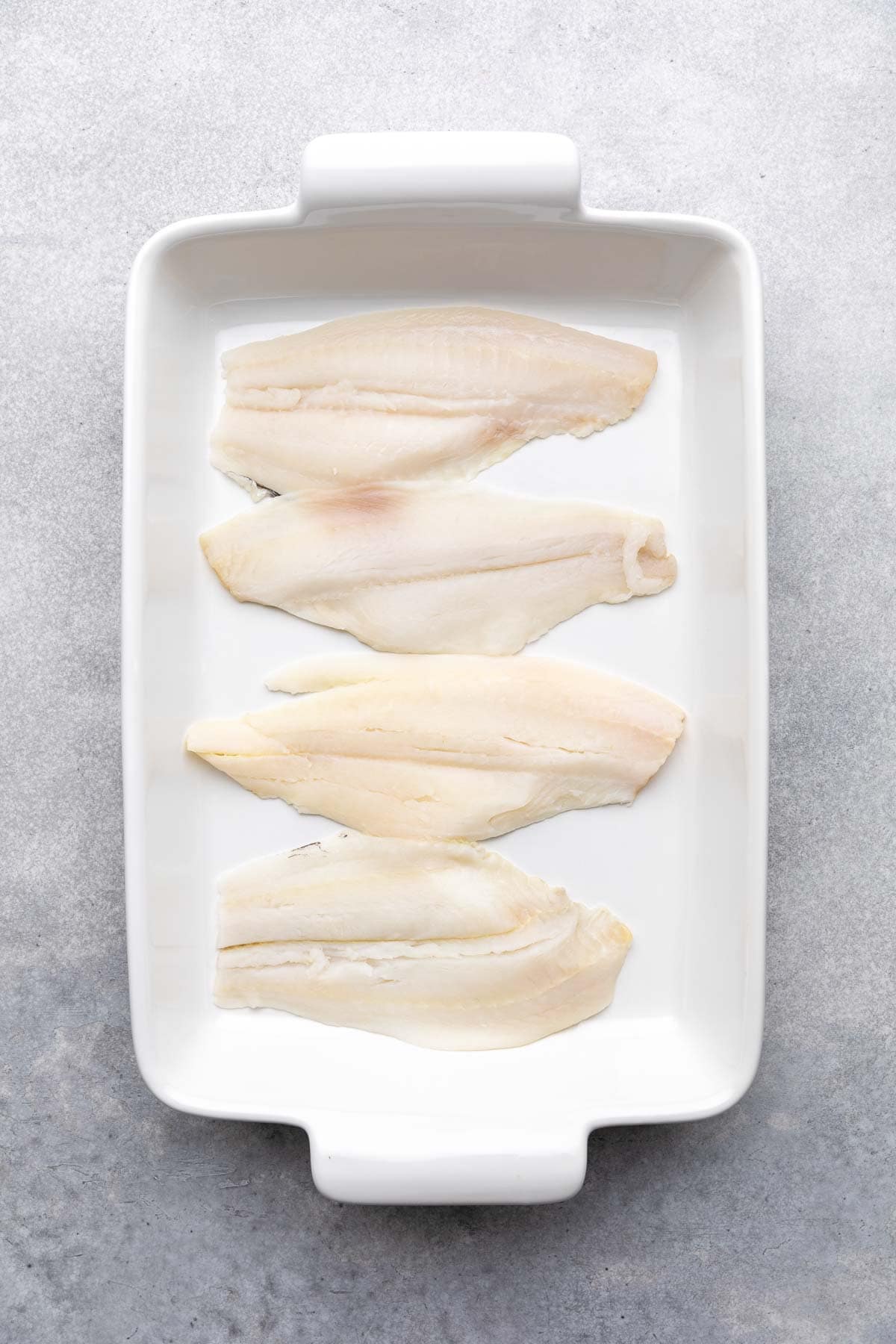 Fish fillets in a white baking dish.